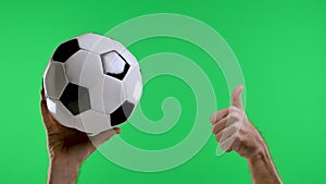 Male hand pointing with index finger and showing thumb up to second hand holding classic black and white soccer ball on