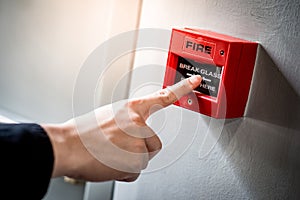 Male hand pointing at red fire alarm switch