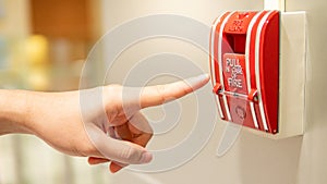 Male hand pointing at red fire alarm switch