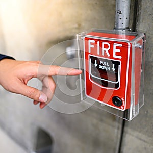 Male hand pointing at red fire alarm switch