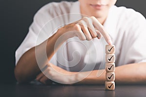 Male hand pointing at a wooden block,check mark symbol,Checklist concept,Survey concepts through questionnaires, comments to lead