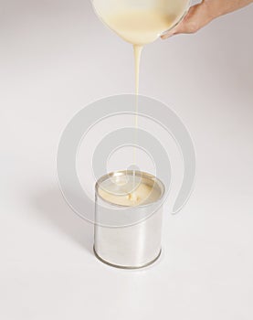 Male hand pouring condensed milk into a tin can