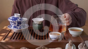 Male hand pouring hot red tea from glass pot in bowl on traditional ceremony. Tea man pouring fresh hot beverage on