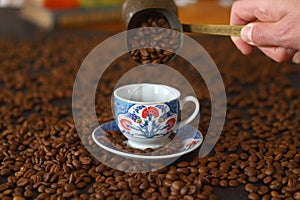 Male hand pouring Turkish coffee. cup of coffee with beans