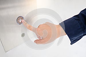 Male hand pressing on down symbol button of elevator