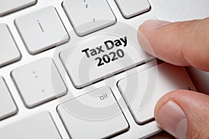 Male hand pressing keyboard key.Tax day 2020