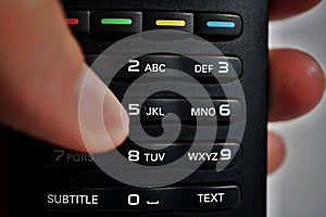 Male hand pressing numerical keyboard in the remote control as symbol of choice and home entertainment when watching television