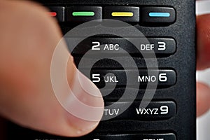 Male hand pressing numerical keyboard in the remote control as symbol of choice and home entertainment when watching television