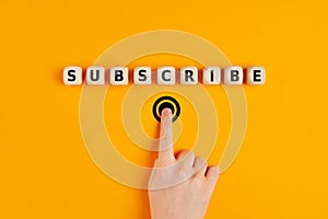 Male hand pressing subscription button with the word subscribe written on wooden blocks. Concept of online registration