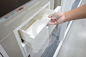 Male hand pulling and opening drawer on white wooden cabinet