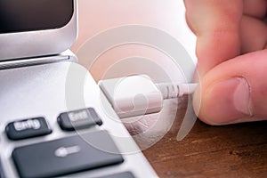 Male Hand Pulling Out A White USB Cable Of The USB Port Of A Laptop