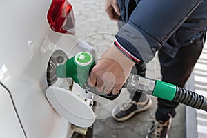 Male hand pumping gas at gas station.