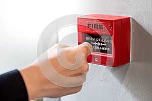 Male hand punching red fire alarm switch