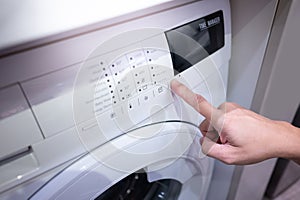 Male hand pushing button on washing machine
