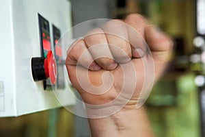 Male hand pushing emergency stop button.