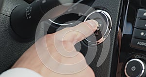 Male hand pushing power button to start keyless ignition hybrid car engine
