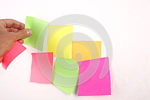 Male hand put a blank paper sticky note on the wall with copy space for your text