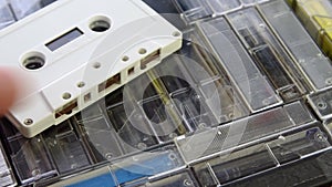 Male hand put down white audio cassette on a set of audio cassettes in cases