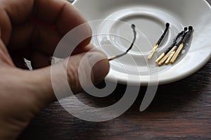 The male hand puts a burnt match in a white porcelain saucer