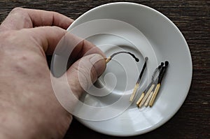 The male hand puts a burnt match in a white porcelain saucer