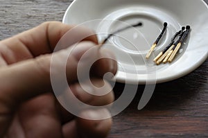 The male hand puts a burnt match in a white porcelain saucer