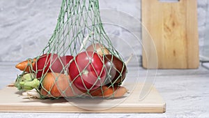 Male hand puts a reusable textile string bag with vegetables