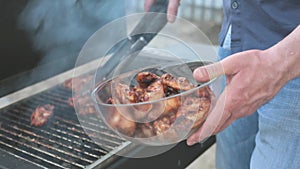 Male hand putting chicken wings into a plate