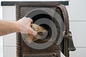 Male hand putting firewood in opened firebox