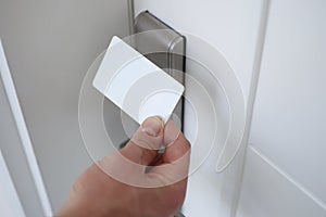 Male hand putting key card to lock on door closeup