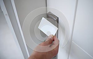 Male hand putting key card to lock on door closeup