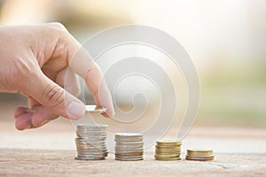 Male hand putting money coin stack growing business