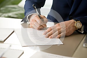 Male hand putting signature on contract, signing document, close