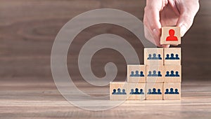 Male hand putting wood cube leader on pyramid