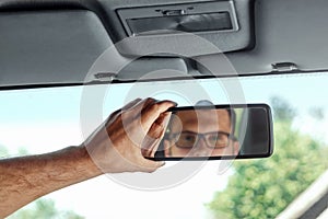 Male hand on the rearview mirror of a car, close-up. Manual adjustment of a rear-view mirror