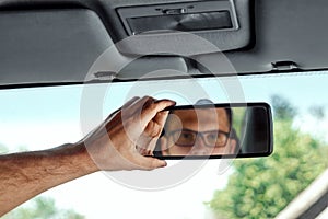 Male hand on the rearview mirror of a car, close-up. Manual adjustment of a rear-view mirror
