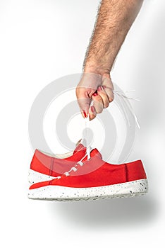 Male hand with red fingernails holding red sneakers