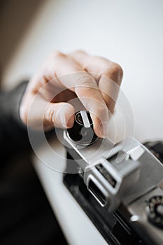 Male hand reloading film retro camera on a white table. Horizontal
