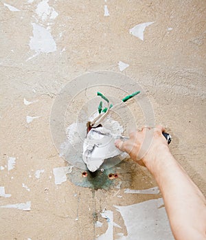 Male hand repairs wall with spackling paste.