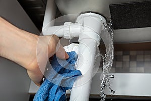 Male Hand`s Holding Blue Napkin Under Leakage Pipe