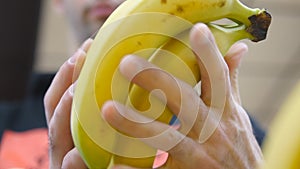 Male hand selecting bananas at the supermarket. Man taking a bunch of bananas from counter in a grocery store. Guy