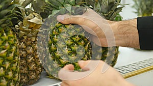 Male hand selecting pineapple at the supermarket. Man taking pineapple from counter in a grocery store. Guy selecting