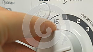 A male hand setting and turning high end electronic Washing Machine on.