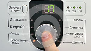 A male hand setting and turning high end electronic Washing Machine on.