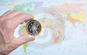 Male hand showing compass on the world map background