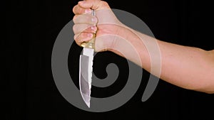 Male hand showing knife with sharp blade and decorative handle, black background