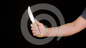 Male hand showing knife with sharp blade and wooden handle on black background