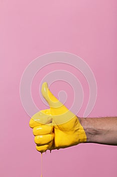 Male hand showing sign thumb up with paint flowing down on a colored background. creative idea, creative concept, gesture