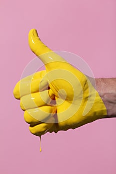 Male hand showing sign thumb up with paint flowing down on a colored background. creative idea, creative concept, gesture