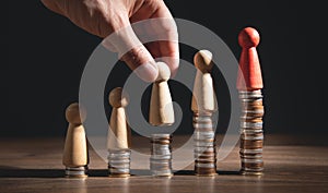 Male hand showing wooden human figure on coins stack