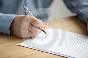 Male hand signing document, senior man putting signature on pape